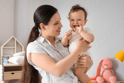 Young mother holding her little baby in bedroom