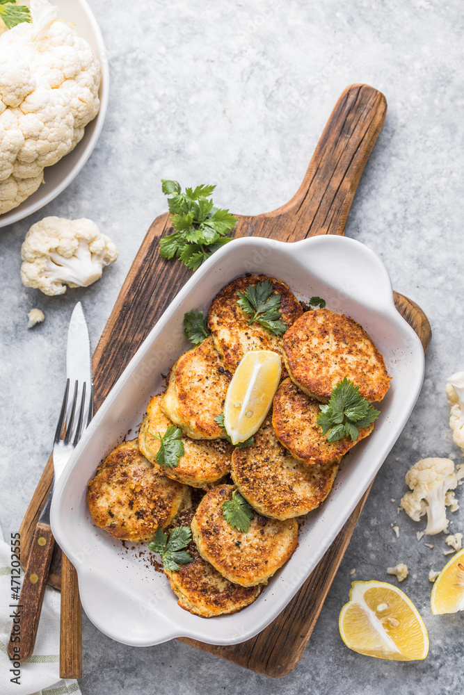 Vegan cauliflower vegetable fritters on the kitchen table. Fried vegetarian cutlets or pancakes. The concept of fast food. Vegan cauliflower vegetable fritters on the kitchen table. Fried vegetarian cutlets or pancakes. The concept of fast food.