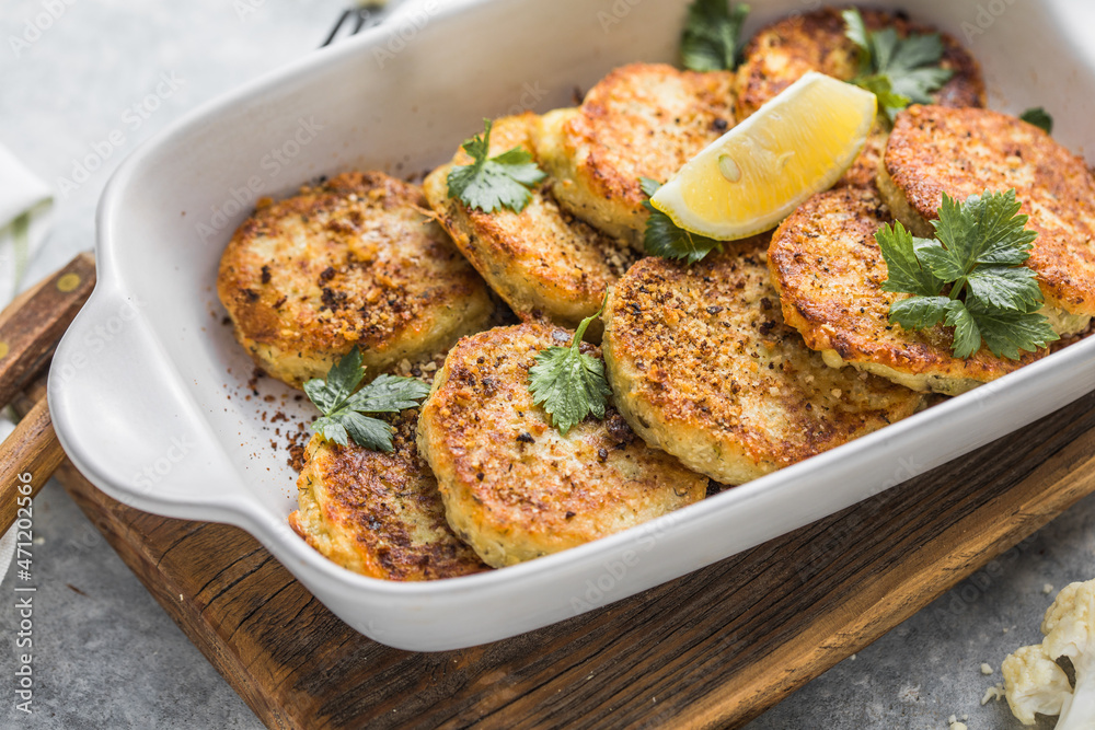 Vegan cauliflower vegetable fritters on the kitchen table. Fried vegetarian cutlets or pancakes. The concept of fast food. Vegan cauliflower vegetable fritters on the kitchen table. Fried vegetarian cutlets or pancakes. The concept of fast food.