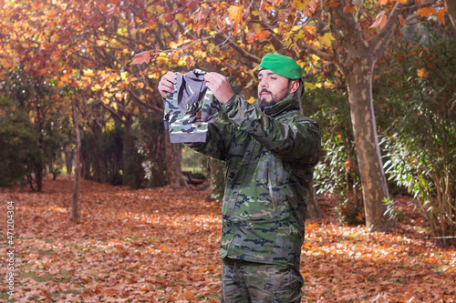 Hombre militar levanta y mira la ropa de su futuro bebé en un bosque de otoño