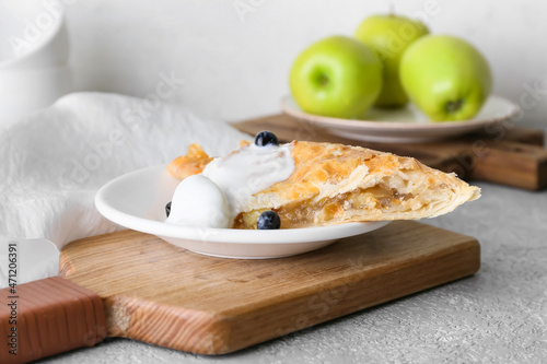 Plate with piece of tasty apple strudel on light background