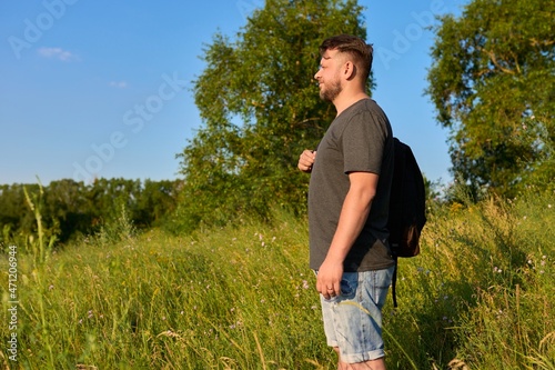 Middle-aged bearded man with a backpack on a hike looking at the horizon