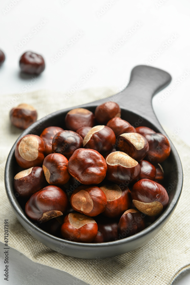 Obraz premium Frying pan with chestnuts on white background, closeup
