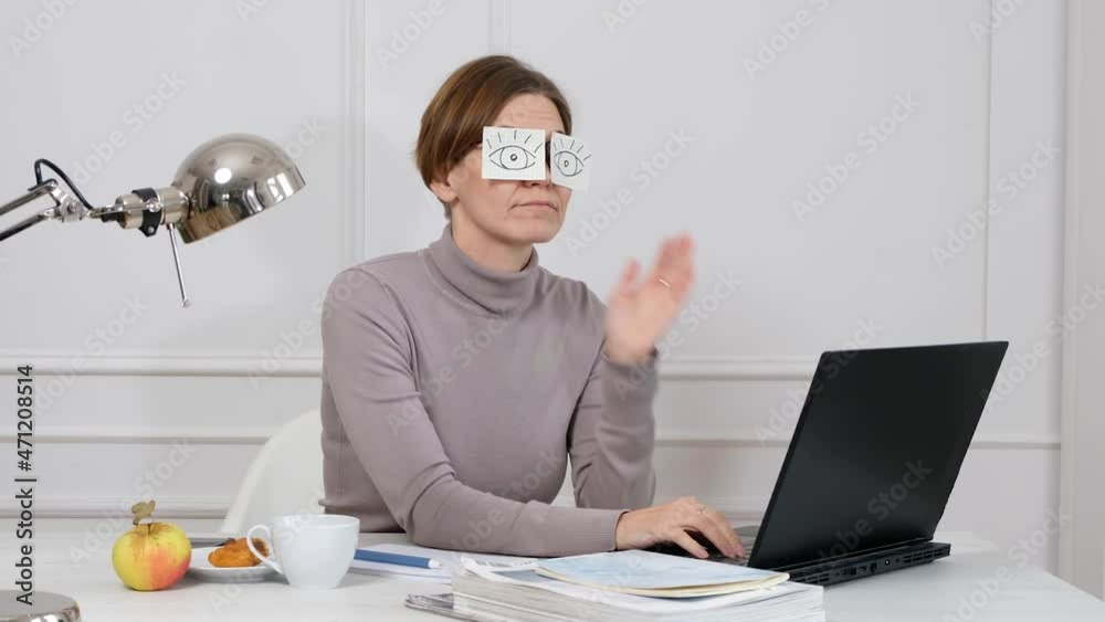 Funny tired female employee napping at office workplace covering eyes with sticky notes.