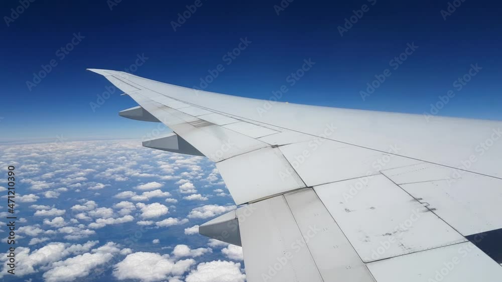 Airplane Wing Flying Above Clouds and Earth Landscape Under Blue Sky, Passenger Window Point of View Airplane Wing Flying Above Clouds and Earth Landscape Under Blue Sky, Passenger Window Point of View