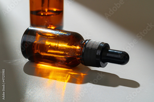 Amber glass bottles for cosmetics, natural medicine or essential oils on gray background