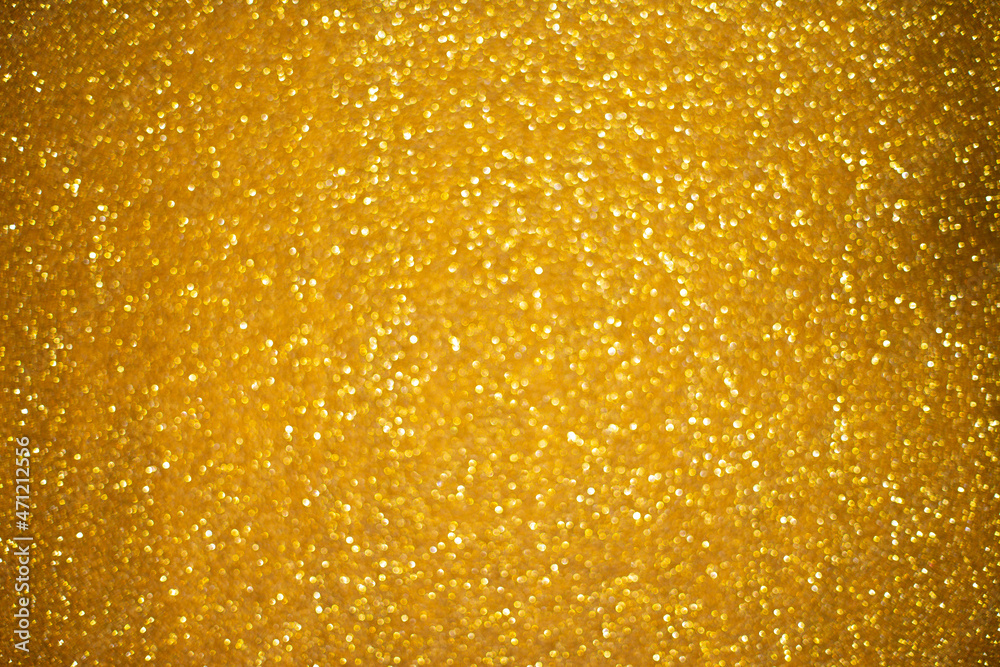 Gold glitter sparkles with bokeh effect. Festive background with bright golden lights. Christmas mood concept. Copy space texture, flat lay. Defocus blur.