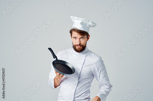 Fototapeta a man in a chef's uniform with a frying pan in hand Professional