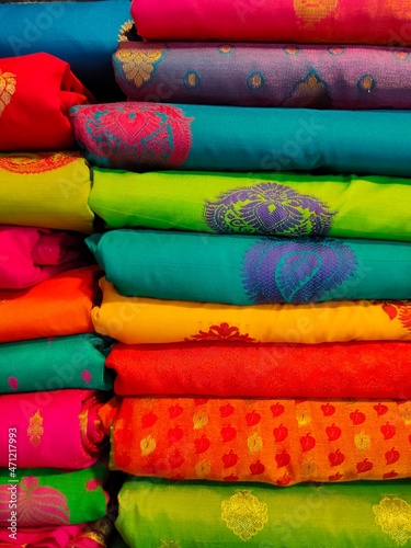 Closeup view of stacked colours saris or sarees in display of Indian retail shop, textile shop. © Vinayak Jagtap