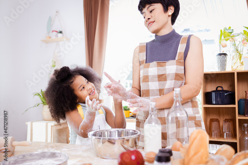 Happy African American mother and daughter having fun while preparing cookie dough at home. happy family time.