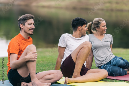 Relaxed group of friends sitting on a yoga mat in a park