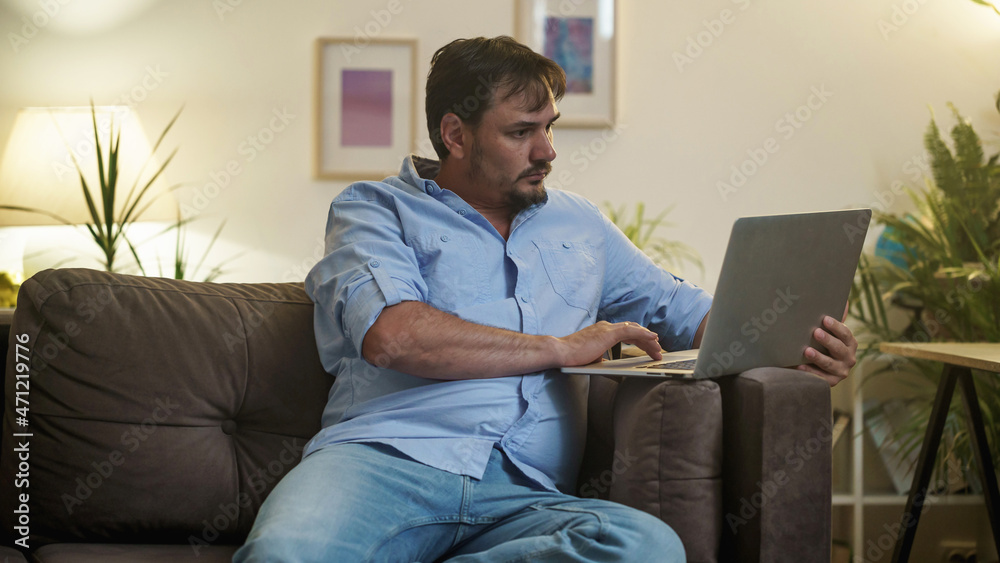 tired male businessman works at home at night on a laptop, works from a home office, studies online,. Internet addiction or a person who works late. a frightened man works late at his home office tired male businessman works at home at night on a laptop, works from a home office, studies online,. Internet addiction or a person who works late. a frightened man works late at his home office