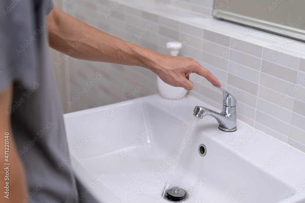 The faucet in the bathroom with running water. Man keeps turn off the ...