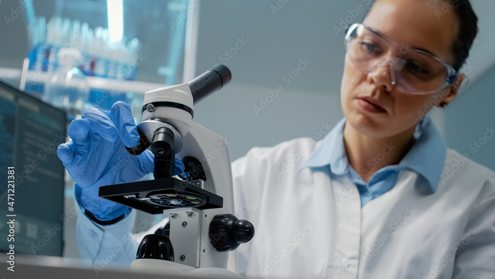 Portrait of specialist using scientific microscope in laboratory with lens with magnifying glass for dna and bacteria test. Doctor wearing gloves studying sample with biological equipment Portrait of specialist using scientific microscope in laboratory with lens with magnifying glass for dna and bacteria test. Doctor wearing gloves studying sample with biological equipment