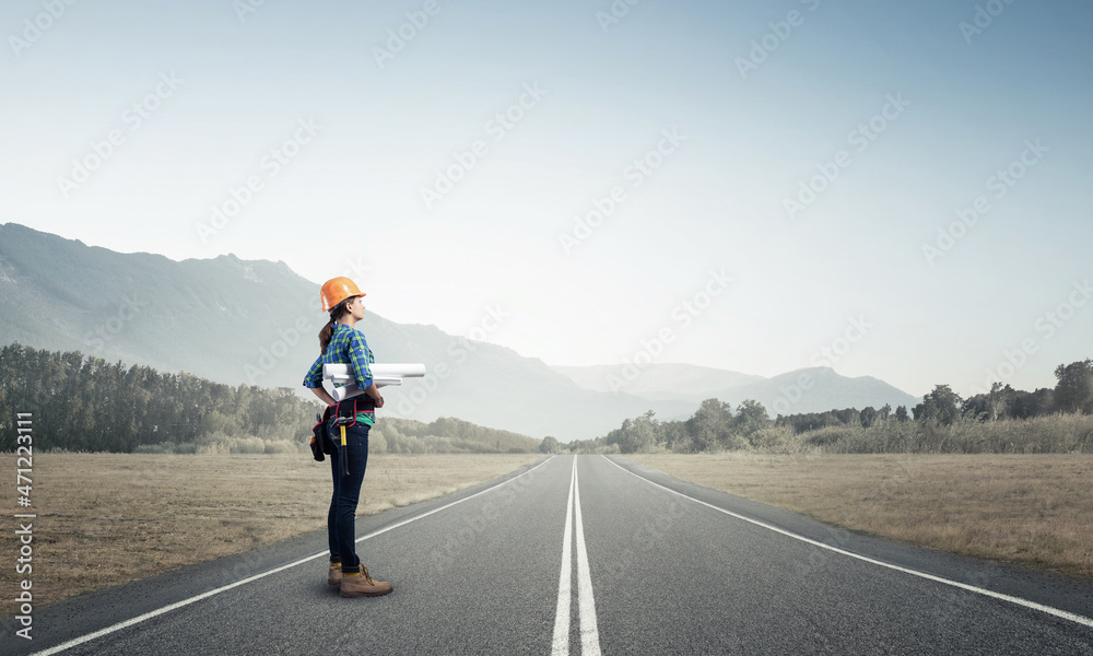 Young woman in safety helmet standing on road Young woman in safety helmet standing on road