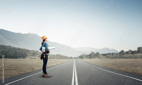 Young woman in safety helmet standing on road