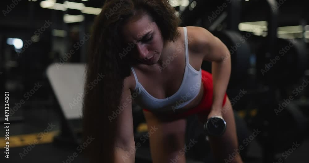 Fit woman trains muscles, lifting dumbbell in the gym Fit woman trains muscles, lifting dumbbell in the gym