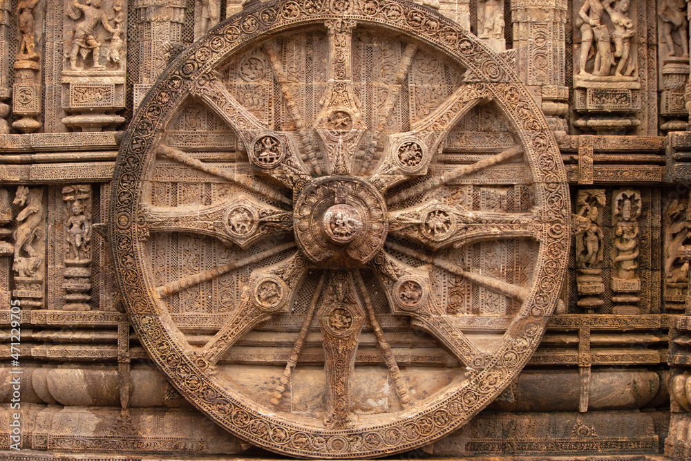 Chariot wheel with eight spokes with a central medallion. The medallions on the wheel spokes are richly carved depicting numerous deities and erotic and amorous figures Konark Sun Temple, Orissa