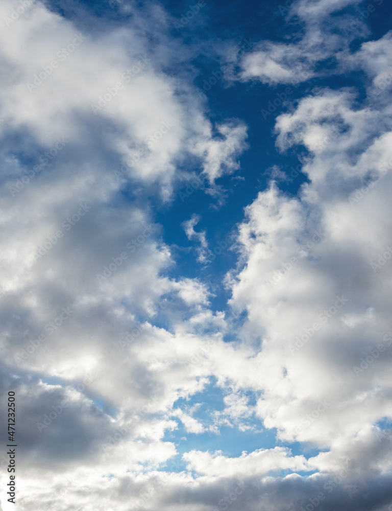 Big white fluffy clouds in the blue sky in sunny weather, vertical format Big white fluffy clouds in the blue sky in sunny weather, vertical format