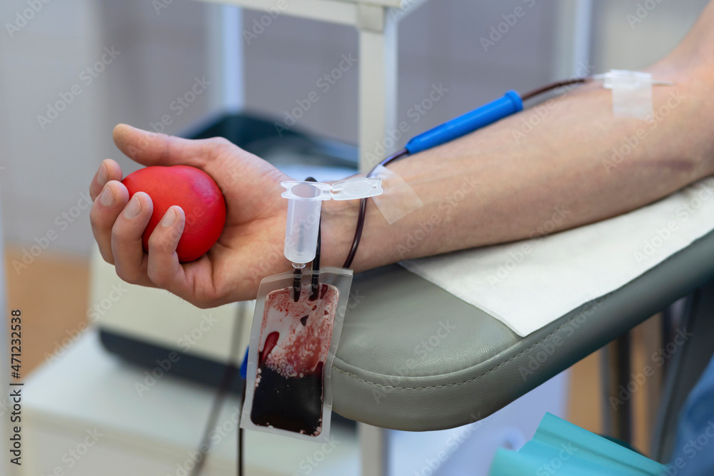 bone marrow donation. male hand holding red ball, blood transfusion system, blood bag.  closeup