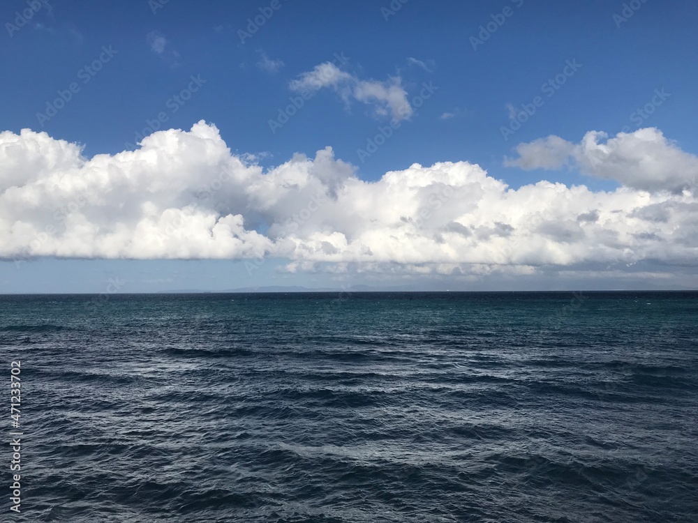 Amazing white clouds of type cumulus over dark blue colored ocean.