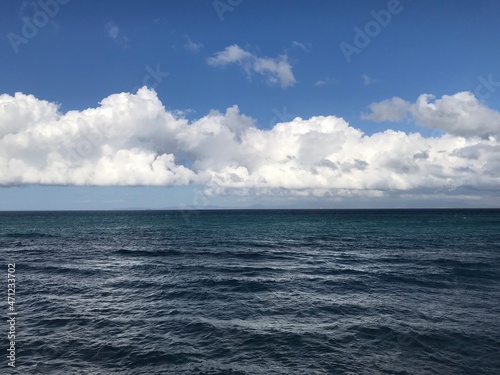 Amazing white clouds of type cumulus over dark blue colored ocean. © Rkyomar