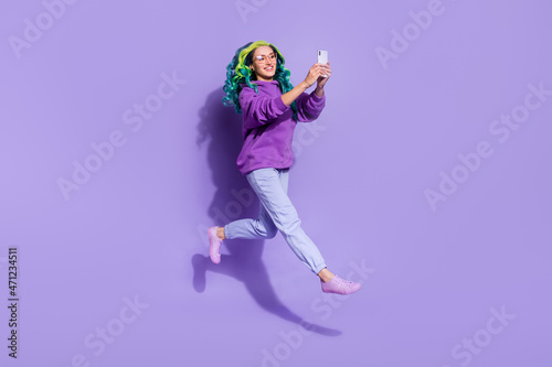 Full size photo of vibrant haired lady blogger jump use digital smart phone make selfie isolated over purple color background