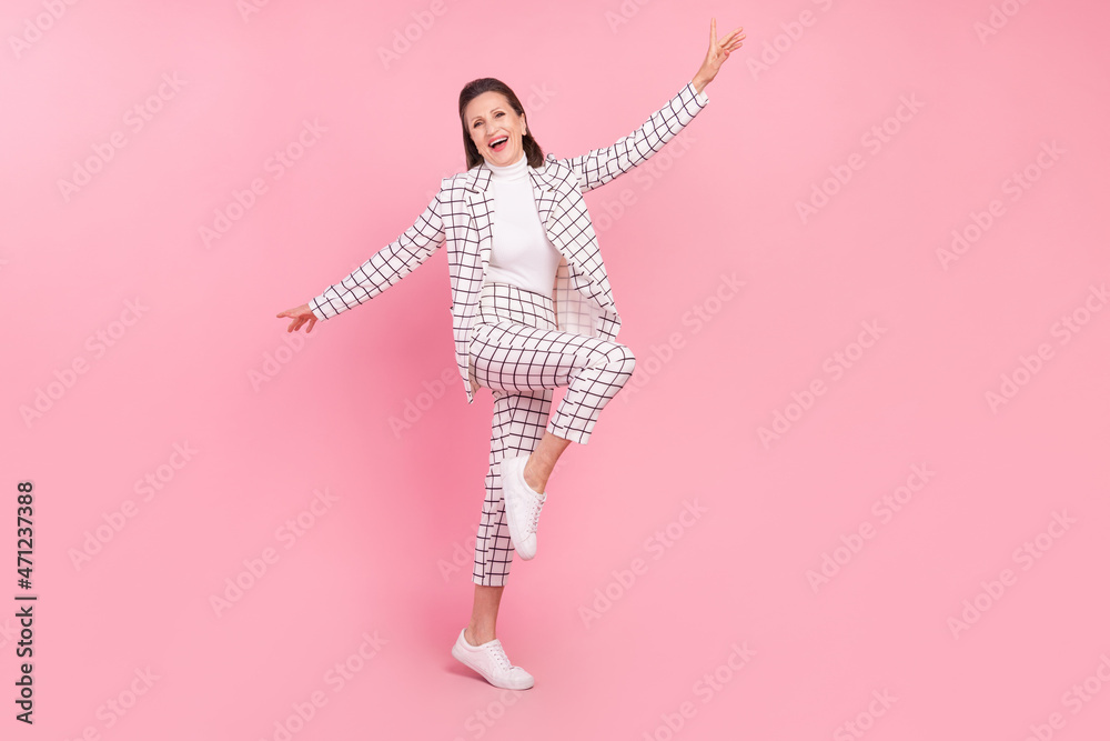Full size image of cheerful mature lady dancing energetic businesswoman isolated on pink color background Full size image of cheerful mature lady dancing energetic businesswoman isolated on pink color background
