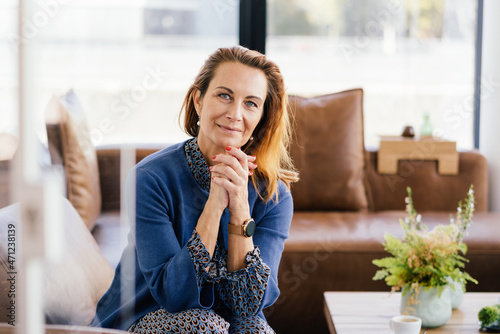 Bild auf Leinwand Serious woman sitting with clasped hands looking at camera
