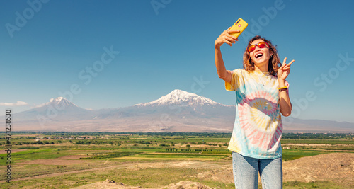 Tourist woman on the viewpoint taking selfie photo on her smartphone at the famous Mountain Ararat. Travel and Tourism in Armenia