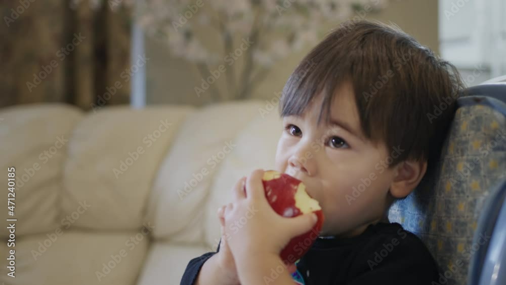 Two-year-old kid eats a big red apple Two-year-old kid eats a big red apple