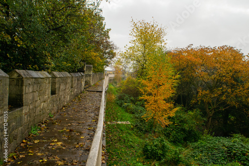 Trail on top of medieval 13th century city wall through colorful autumn foliage in York England