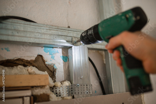 Drives screws into the holder. Close-up, hand with a screwdriver tightening the fastening screw. work with a drill. home repairs. Selective focus