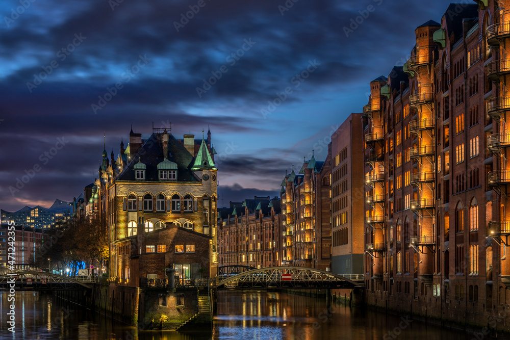 Hochauflösende Aufnahme mit hoher Dynamik der alten beleuchteten Speicherstadt in Hamburg nach Sonnenuntergang zur frühen blauen Stunde im November 2021