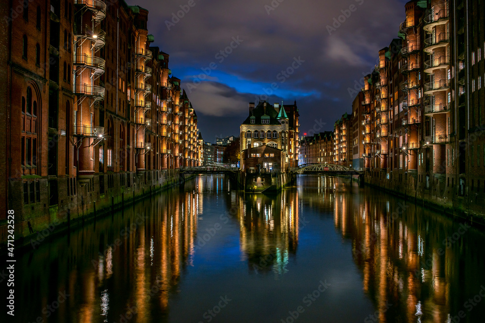 Detailliertes Panoramafoto der beleuchteten Speicherstadt in Hamburg mit Reflexionen der Lichter im Wasser (November 2021)