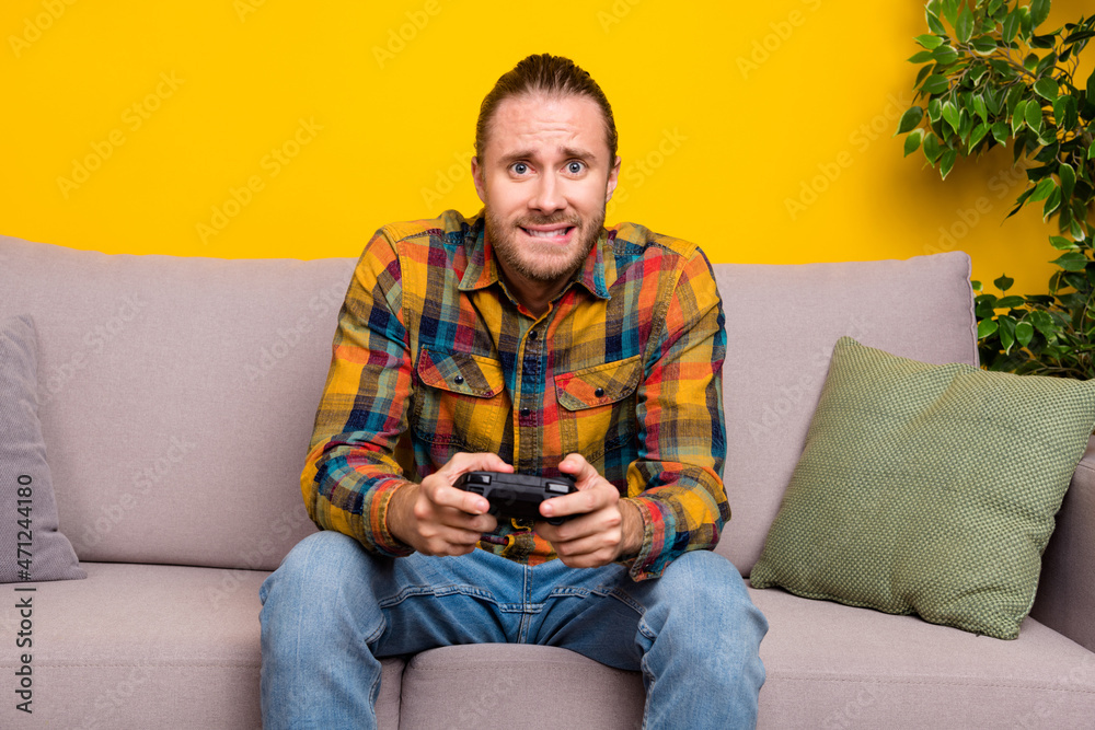 Photo of nervous guy sit divan play intense video game competition wear plaid shirt isolated yellow color background