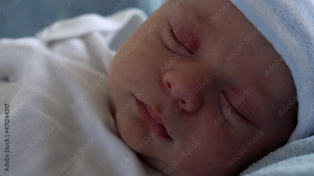 Close-up of Newborn Baby Face Portrait Early Days in Macro Sleeping On Blue Star Background. Child At Start Minutes Of Life on Hat. Infants, Childbirth, First Moments Of Borning, Beginning Concept