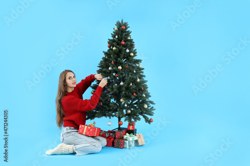 Attractive woman, Christmas tree and gift boxes on blue background