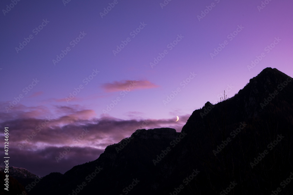 Crescent moon over mountain at dusk