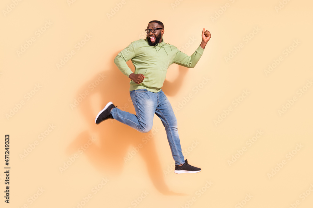 Full length photo of energetic active man jumping have fun celebrate luck isolated on beige color background