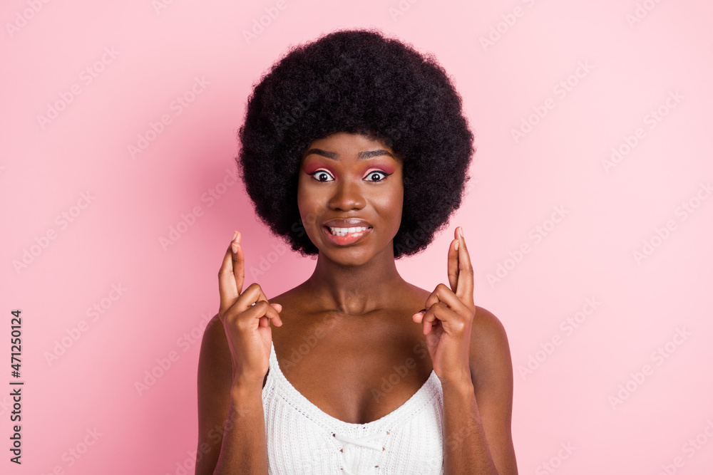 Photo portrait curly girl in white top biting lip crossed fingers hope isolated pastel pink color background Photo portrait curly girl in white top biting lip crossed fingers hope isolated pastel pink color background