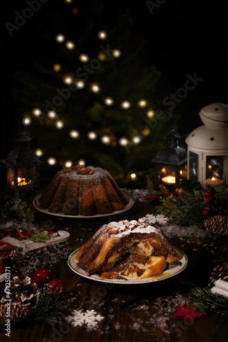 Traditional homemade chocolate christmas cake with orange candied fruits powdering with icing sugar. Lignts bokeh background