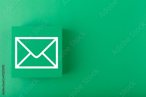 Email concept. Envelope drawn on toy square against dark green background with copy space. Concept of  marketing, newsletter, promotion information and virtual communication concept. 