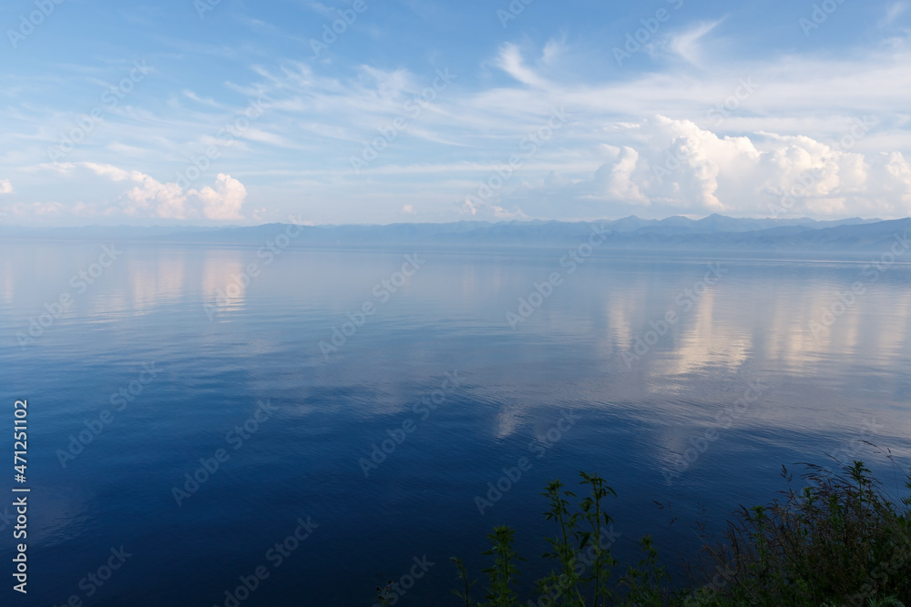 Lake Baikal in the evening. Water and beautiful white clouds. The clouds are reflected in the water.