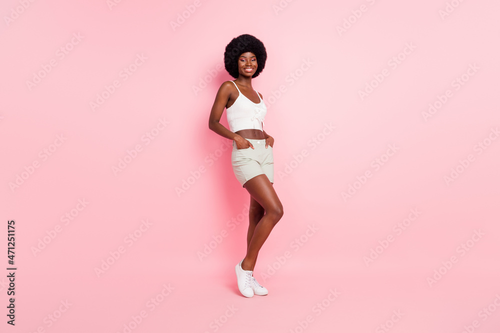 Full size photo of sweet young curly hairdo lady wear white top shorts isolated on pastel pink color background Full size photo of sweet young curly hairdo lady wear white top shorts isolated on pastel pink color background