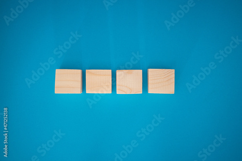 Fototapeta Naklejka Na Ścianę i Meble -  Top view of blank four wooden cubes on a blue background with space for text