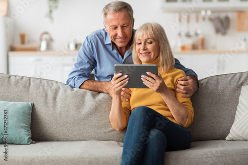 Happy Senior Couple Using Digital Tablet Browsing Internet At Home