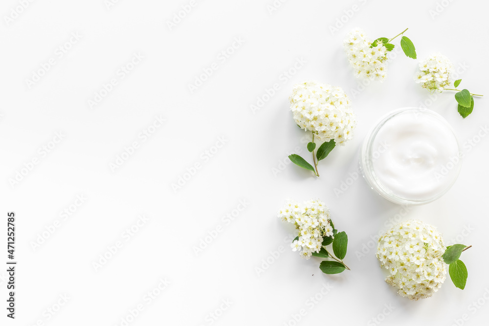 White blossoms flowers with skin cream in glass jar