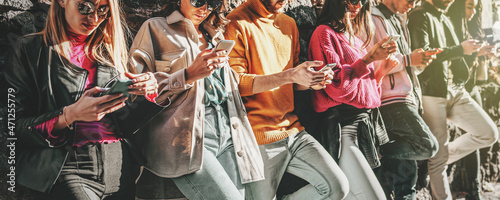 A group of young digital native people using smartphone together - friends phubbing and addiction to cellphones concept photo