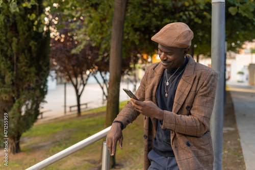 Hombre mirando su teléfono móvil, con expresión alegre, en el parque.